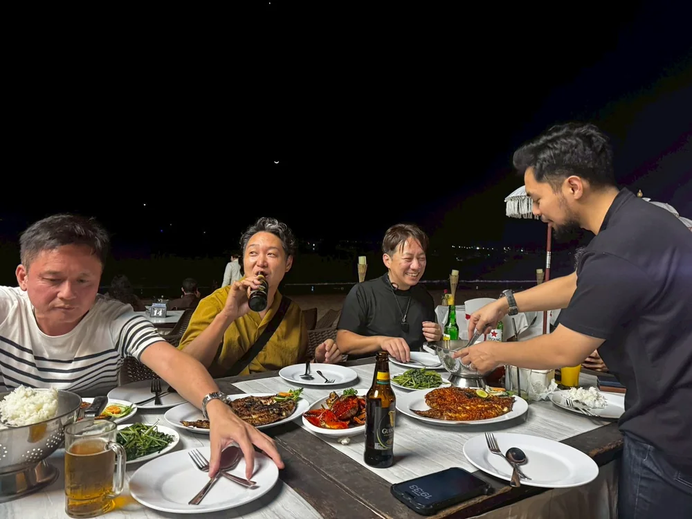 Participants laughing together over dinner by the sea